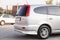 Rear trunk and bumper view of a Honda Stream car in a silver body Japanese 2002 year van in a parking lot with a green trees and