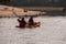 Rear of two people kayaking in a sunlit river