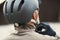 A rear view of active senior man standing outdoors in town, putting on a bike helmet.