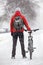 Rear view of an adult man with mountain bicycle standing on snowy bike lane on an urban streets, winter season with snowfall