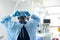 Rear view of african american male surgeon in gown and gloves tying on mask in theatre, copy space