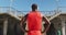 Rear view of african american man with headphones on, standing, taking break in exercise outdoors