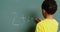 Rear view of African American schoolboy solving math problem on chalkboard in classroom at school 4k
