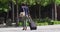 Rear view of african american woman wearing face mask crossing road wheeling suitcase