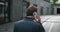 Rear view of ambitious businessman talking on mobile phone and walking through the business district. Back view of