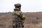 Rear view of armed Ukrainian soldier walking in steppe in uniform and helmet