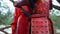 Rear view as a girl in a red kimono unties zapekhki on the armor of the samurai and takes from his hands katana