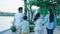 Rear view of Asian family smiling & walking on waterfront promenade at dusk