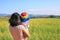 Rear view Asian mother carrying baby at sunnhemp hillside field and looking out mountains at sunny day