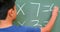 Rear view of Asian schoolboy solving math problem on chalkboard in classroom at school 4k