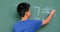 Rear view of Asian schoolboy solving math problem on chalkboard in classroom at school 4k