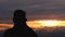 Rear view of Asian senior drinking hot coffee outdoor and enjoying the beautiful sky landscape at sunset on the mountain top.