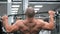 Rear view athlete`s back slow motion Pull upper block chest sports equipment. Good looking man exercises hard in a gym class conce