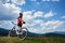 Rear view of athletic sportsman cyclist in sportswear and helmet standing with cross country bike