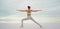 Rear view athletic woman doing yoga, body stretch outdoors on salt coast lake