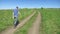 Rear view. bald villager in tarpaulin boots walking on a field road