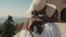 Rear view of beautiful female tourist in a straw hat. Strong wind blowing, hair flutters. Woman holds up her hat.