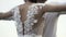 Rear view of a beautiful white wedding dress of a young slim bride with gentle flowers and cutout back. Action. loving