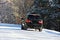 Rear view of a black jeep car driving on a snow-covered highway