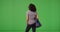 Rear view of black woman with big blue polka dot bag standing on green screen
