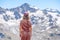 Rear view of a blonde in a baseball cap posing against a background of snowy mountain peaks of the Caucasus