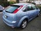 Rear view of a blue Ford Focus MK2 car from 2005 parked in the street with dents and scratches