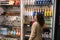 Rear view of brunette traveler woman looking at stalls with different food items and goods while shopping in duty free shop in