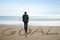 Rear view businessman standing with goal word on sand beach