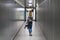 Rear view of a casual female traveler walking narrow an airport corridor.