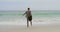 Rear view of Caucasian Businessman jumping with briefcase on the beach 4k