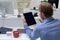 Rear view of caucasian businessman sitting at desk waving making video call using tabet