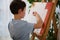 Rear view of Caucasian dark-haired school boy drawing at home. Kids education, entertainment, hobby, ar class, drawing, painting