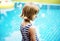 Rear view of caucasian girl standing alone by the pool
