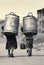 Rear view of children carrying heavy water canisters and cans. Created with generative AI