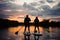 Rear view on couple of people on sup boards on the river at sunset