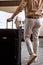 Rear view on cropped business man in elegant wear entering hotel room with suitcase