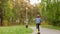 Rear view of cute teenage boy riding skateboard in beautiful green park.