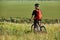 Rear view of the cyclist standing of the hill against beautiful summer landscape.