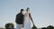 Rear view of diverse bride and groom walking away holding hands at beach wedding, in slow motion