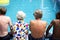 Rear view of diverse senior adults sitting by the pool enjoying