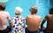 Rear view of diverse senior adults sitting by the pool enjoying summer together