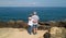 Rear view from a drone of two old people with gray hair. Adult 70 years old. Senior couple looking at the atlantic ocean. Blue