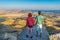 Rear view of family couple standing on mountain cliff and admiring beautiful landscape of coastal valley and sea. Tourists man and