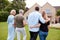 Rear View Of Family With Senior Parents And Adult Offspring Walking And Talking In Garden Together