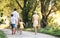 A rear view of family with small children walking barefoot on a road in summer.