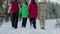 Rear view family walking on snowy path in winter forest low angle view. Mom, dad, son and daughter walking in snowy