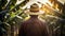 Rear view of farm worker with straw hat standing in banana plantation in spring