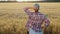 Rear view Farmer girl looking at a wheat field at sunset