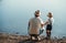 A rear view of father with a small toddler son spending time outdoors by a lake.