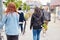 Rear View Of Female Friends With Skateboards And Bike Walking Through City Center